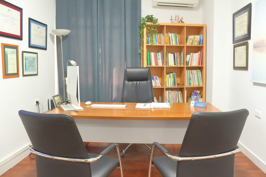 Despacho de psicología de Carmen Irene Jiménez Bujalance, con mesa de trabajo, estantería y diplomas en la pared