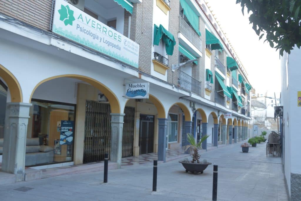 Fachada del Centro Averroes en una calle porticada de Montilla, con el rótulo y los toldos verdes del centro
