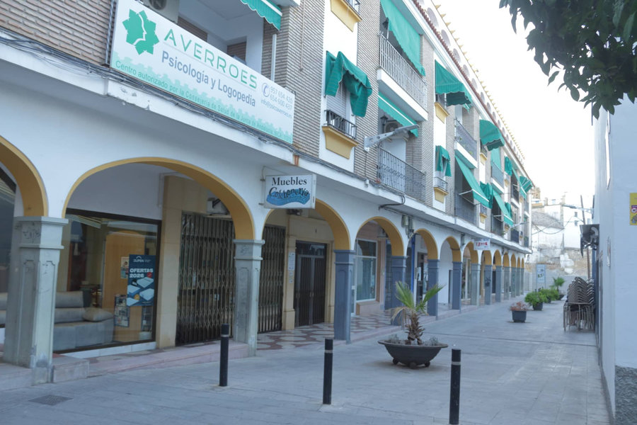 Fachada del Centro Averroes en una calle porticada de Montilla, con el rótulo y los toldos verdes del centro