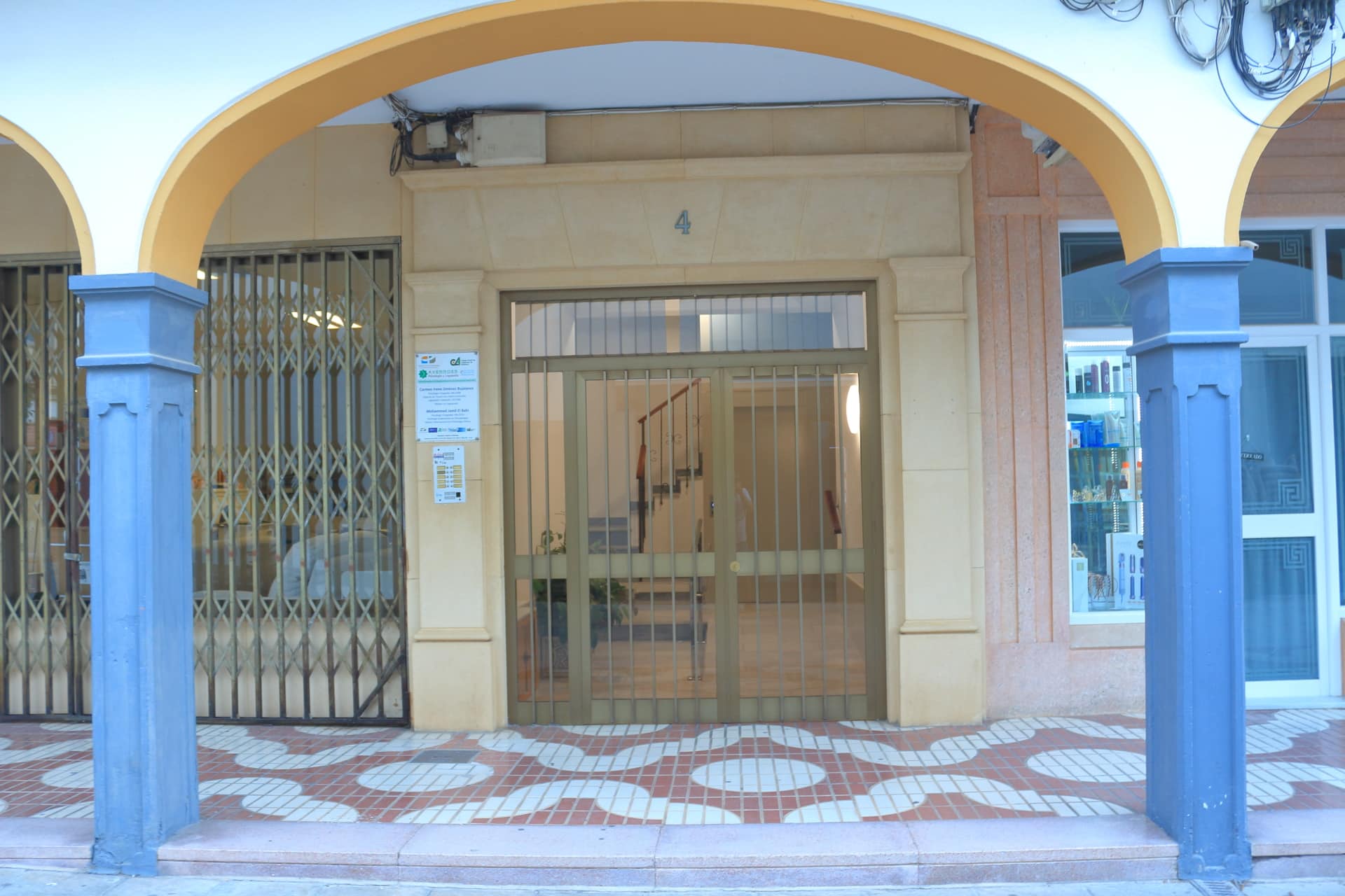 Portal de entrada al Centro Averroes, con columnas azules y puerta de acceso acristalada